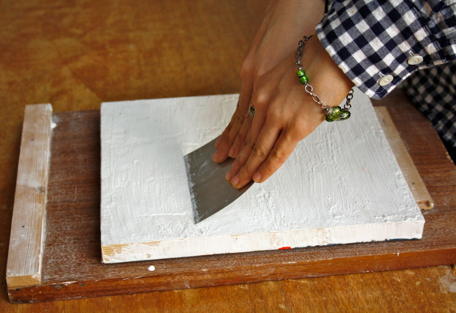 Scraping the gesso smooth using a metal scraper